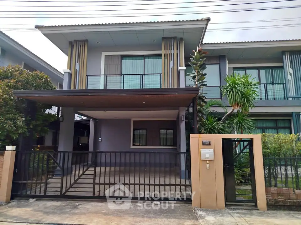 Modern two-story house with gated entrance and lush greenery