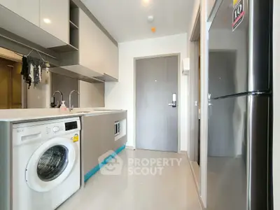 Modern kitchen with sleek appliances and washing machine in stylish apartment.