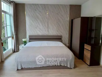 Elegant bedroom with large window and modern decor, featuring a cozy bed and stylish wardrobe.