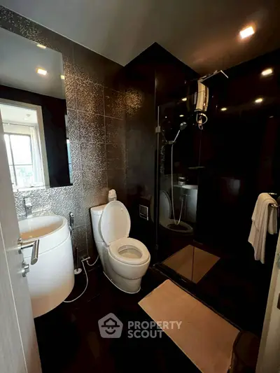 Modern bathroom with sleek black tiles and glass shower enclosure