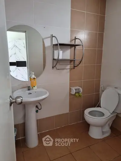 Modern bathroom with pedestal sink and round mirror in stylish apartment.
