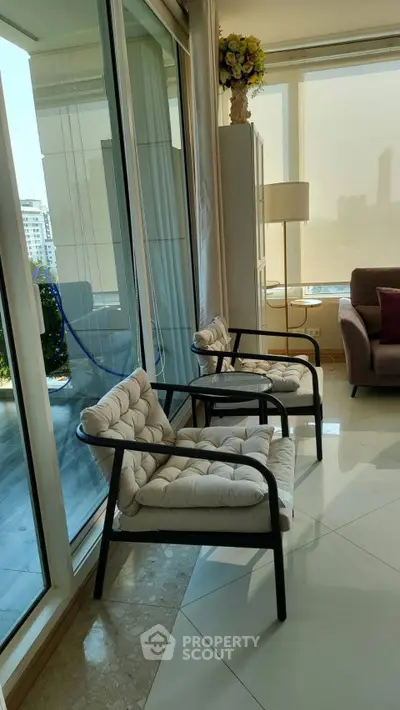 Luxurious living room with modern chairs and floor-to-ceiling windows offering stunning city views.