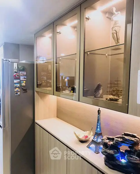 Modern kitchen with sleek cabinets and stainless steel fridge, featuring elegant decor and ambient lighting.