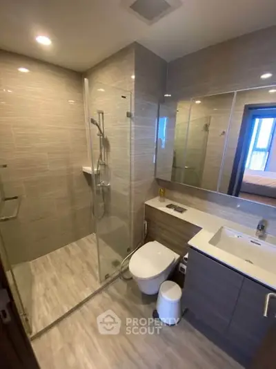Modern bathroom with glass shower and sleek fixtures in contemporary apartment.