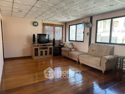 Spacious living room with wooden floors and cozy seating area, perfect for relaxation.