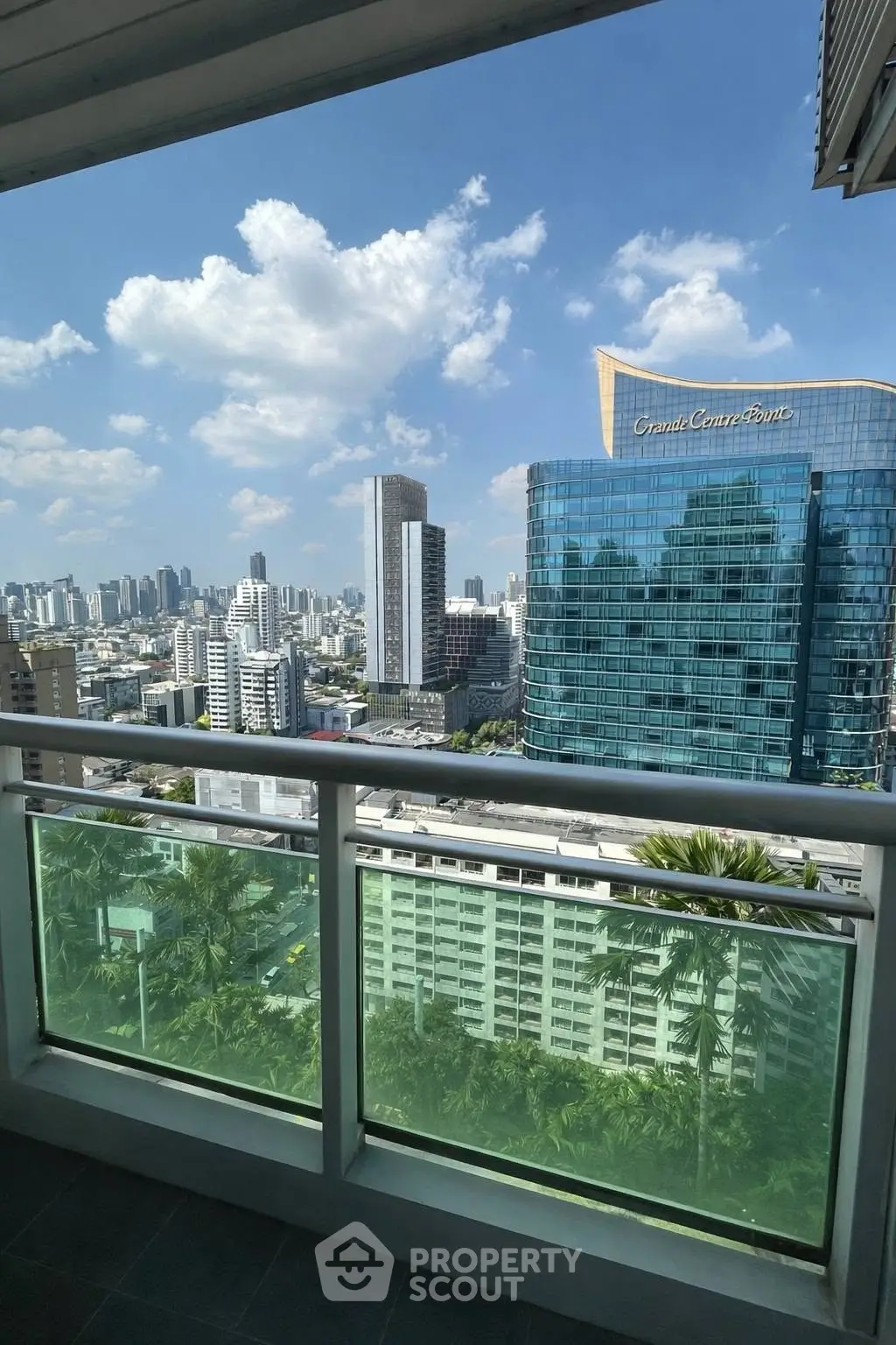 Stunning cityscape view from a high-rise balcony with modern skyscrapers and clear blue sky.