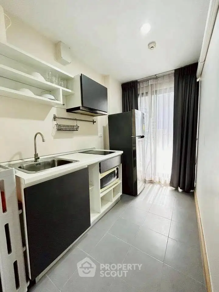 Modern kitchen with sleek black cabinets, open shelving, and natural light from large window.