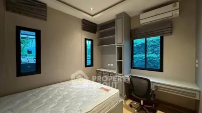 Modern bedroom with built-in desk and air conditioning, featuring large windows for natural light.