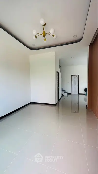Spacious modern living room with elegant chandelier and glossy tiled flooring.