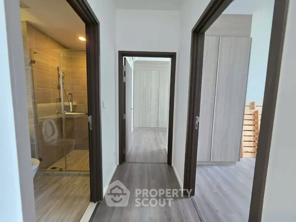 Modern apartment hallway with wooden flooring and bathroom access