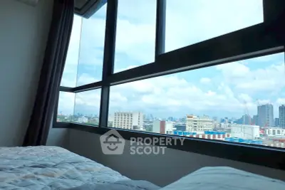 Stunning cityscape view from a cozy bedroom with large windows and natural light.