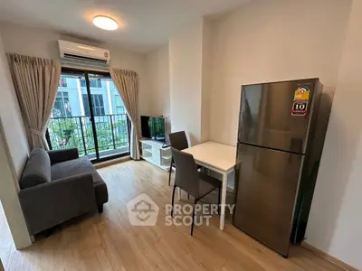 Modern compact living room with balcony, featuring sleek furniture and natural light.
