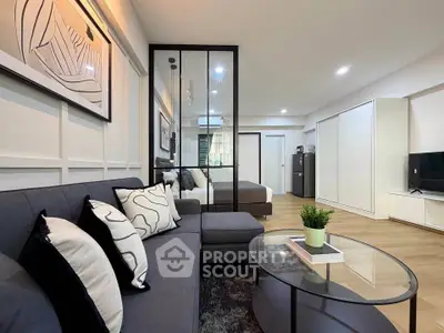 Modern living room with stylish decor and open layout, featuring a cozy sofa and sleek glass coffee table.