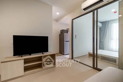 Modern living room with sleek TV stand and sliding glass doors leading to a bright bedroom.