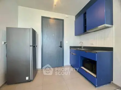 Modern kitchen with blue cabinets and stainless steel fridge in a sleek apartment.