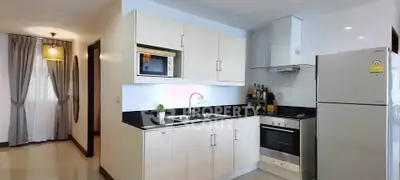 Modern kitchen with sleek cabinetry, built-in oven, and spacious fridge in a bright apartment.