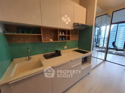 Modern kitchen with sleek cabinetry and open layout, featuring a view of a stylish living area.