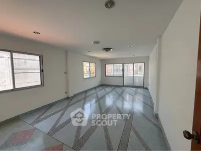 Spacious empty room with large windows and patterned flooring, ideal for customization.