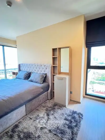Modern bedroom with plush bed, large windows, and stylish decor in a high-rise apartment.