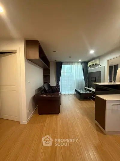 Modern living room with wooden flooring, leather sofa, and large window with curtains.
