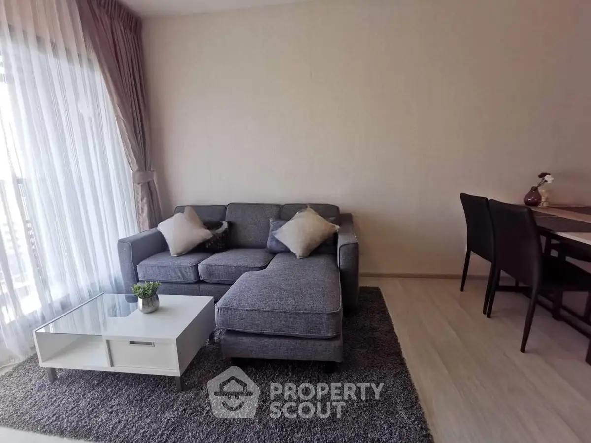 Modern living room with stylish gray sofa and dining area, featuring elegant decor and natural light.