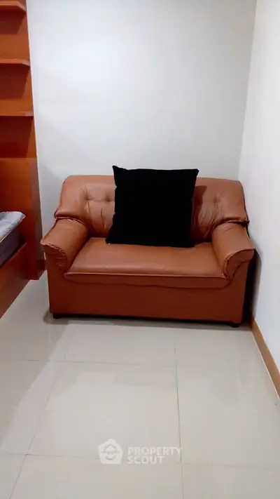 Cozy corner with a brown leather loveseat and black cushion, perfect for relaxation.