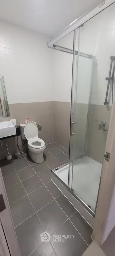 Modern bathroom with glass shower and sleek fixtures in contemporary apartment.