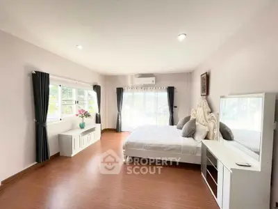 Spacious bedroom with elegant decor and large windows offering natural light.
