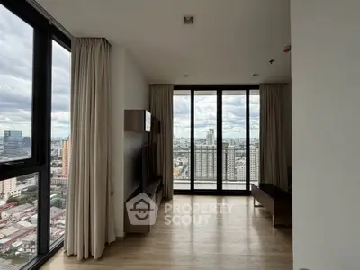 Spacious modern living room with floor-to-ceiling windows offering stunning city views.