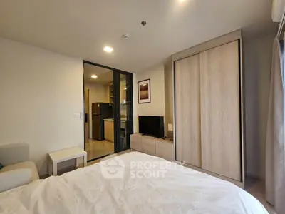 Modern bedroom with sleek wardrobe and open view into a stylish kitchen area.