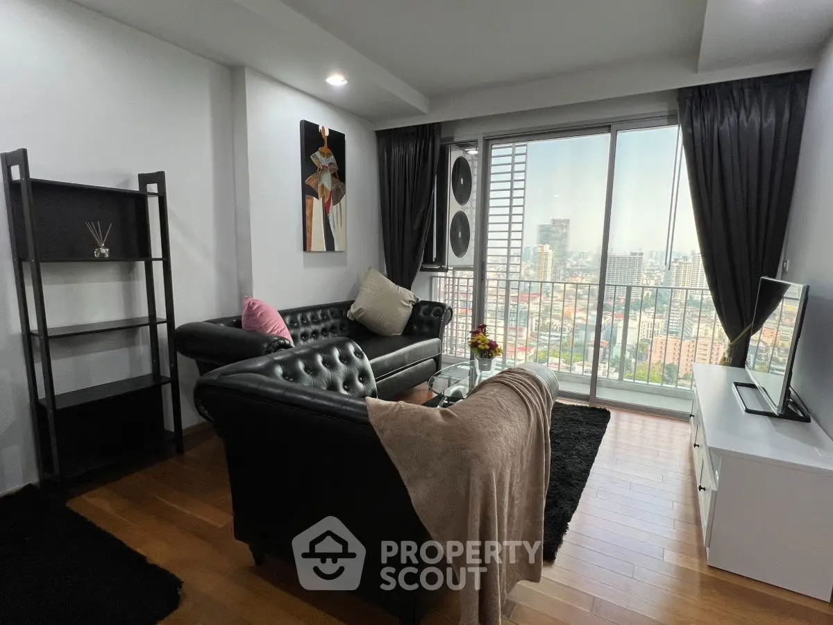 Modern living room with city view, black leather sofas, and wooden flooring.