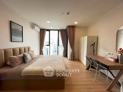 Spacious modern bedroom with large window and stylish decor in a luxury apartment.