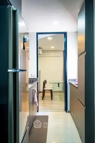 Modern kitchen with sleek appliances and open layout leading to dining area.