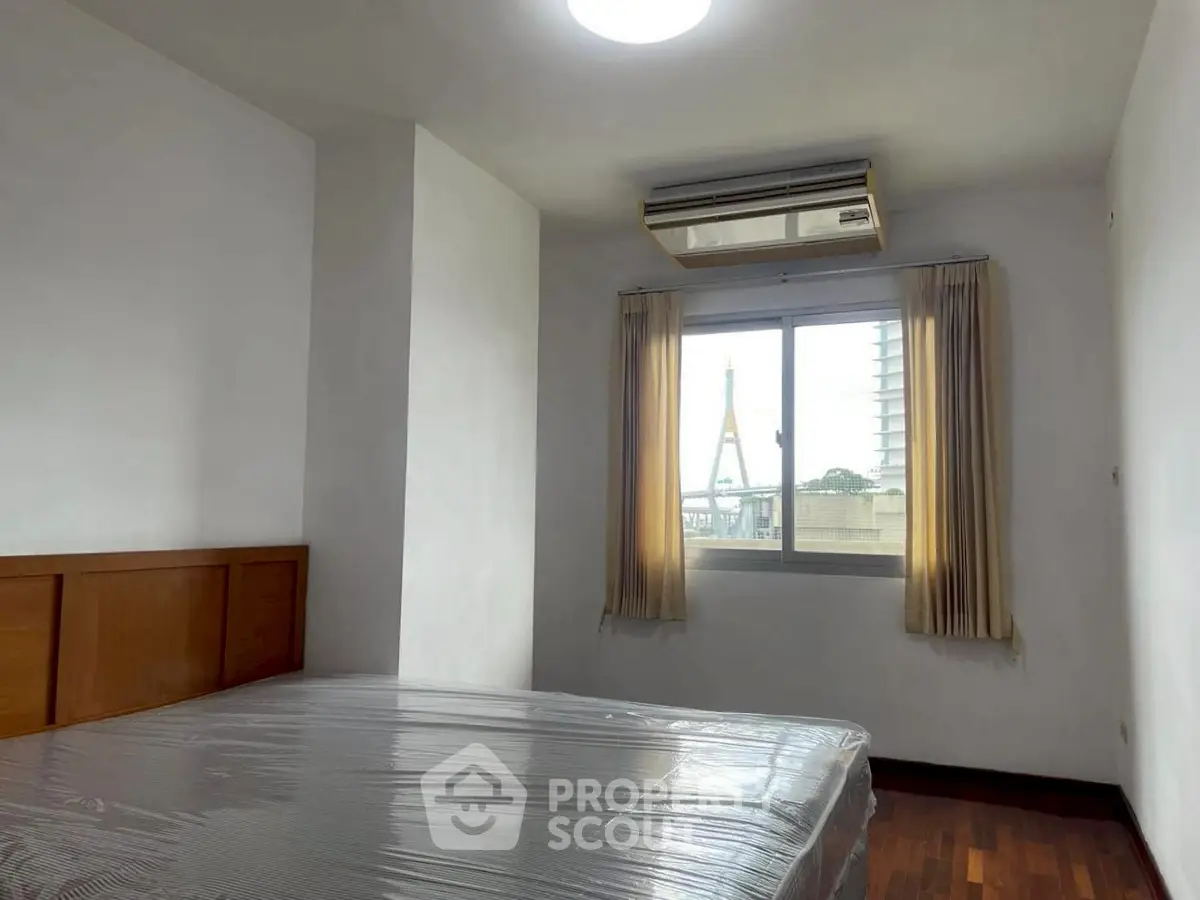 Cozy bedroom with large window offering a city view, featuring a comfortable bed and air conditioning.