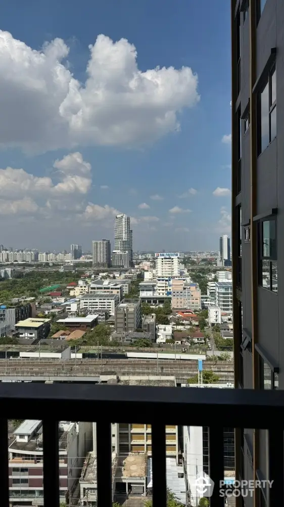 Stunning urban cityscape view from high-rise balcony with clear blue skies and modern architecture.