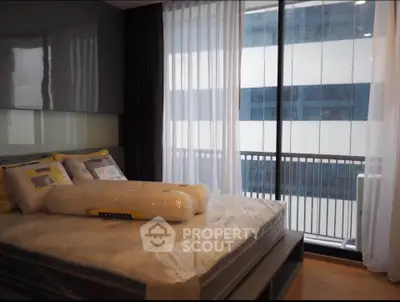 Modern bedroom with large windows and balcony access in a stylish apartment.