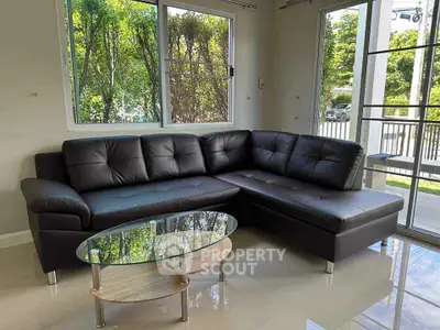 Modern living room with black leather sectional sofa and glass coffee table