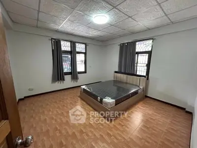 Spacious bedroom with modern bed and large windows in a well-lit room.