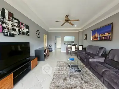 Spacious living room with modern decor and open layout, featuring a ceiling fan and stylish furniture.