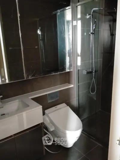 Modern bathroom with sleek fixtures and glass shower enclosure in luxury apartment.