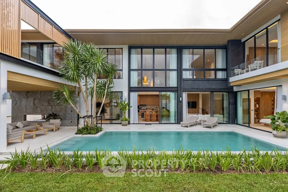 Luxurious modern villa with pool, spacious outdoor seating, and elegant glass facade.