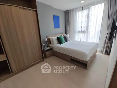 Modern bedroom with large window and wooden wardrobe, featuring stylish decor and ample natural light.