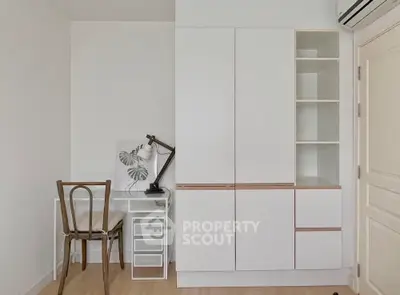 Minimalist study area with sleek white storage and desk lamp.