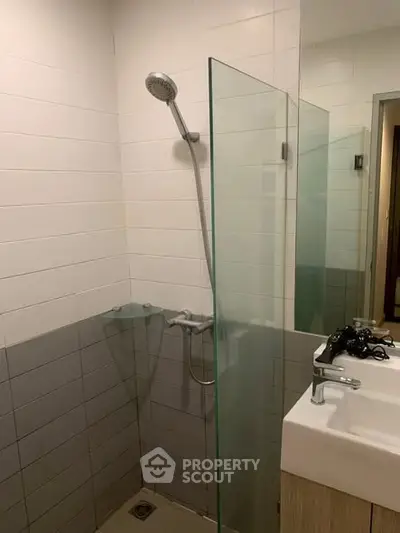 Modern bathroom with glass shower partition and sleek sink design.
