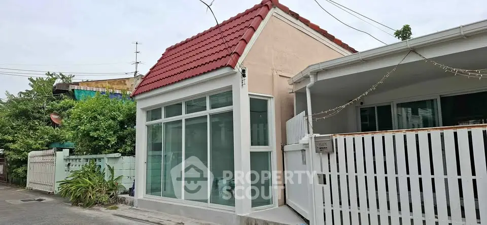 Charming small house with red roof and large windows in a quiet neighborhood.