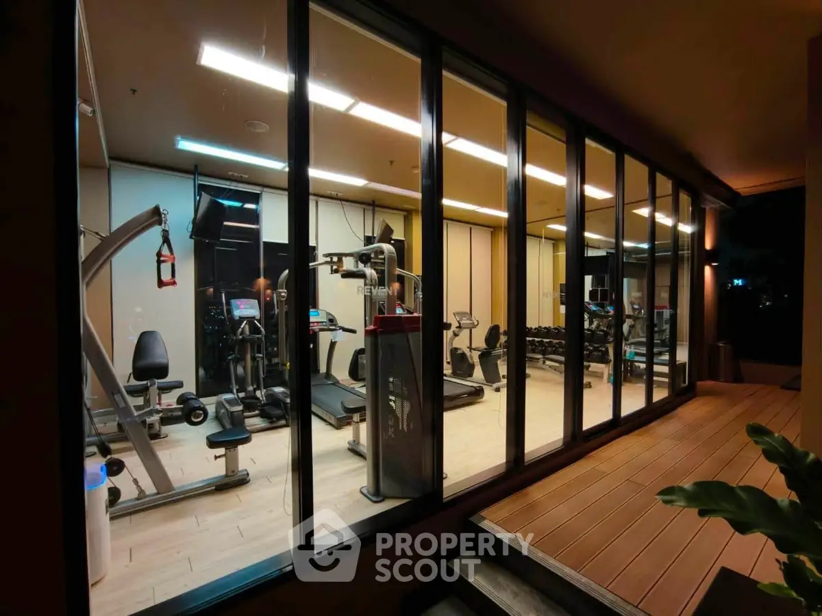 Modern gym with state-of-the-art equipment and floor-to-ceiling windows in luxury building.