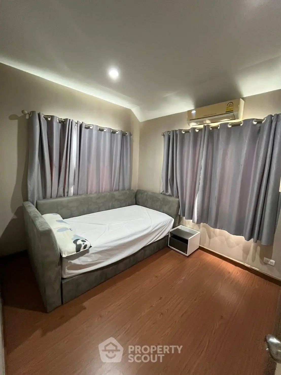Cozy bedroom with wooden flooring and modern furnishings, featuring a comfortable bed and air conditioning.