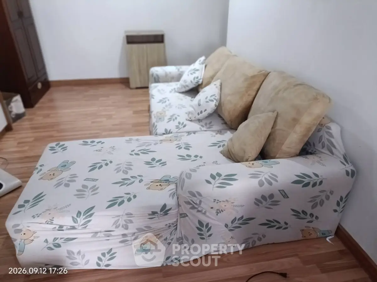 Cozy living room with floral sofa and wooden flooring, perfect for relaxation.