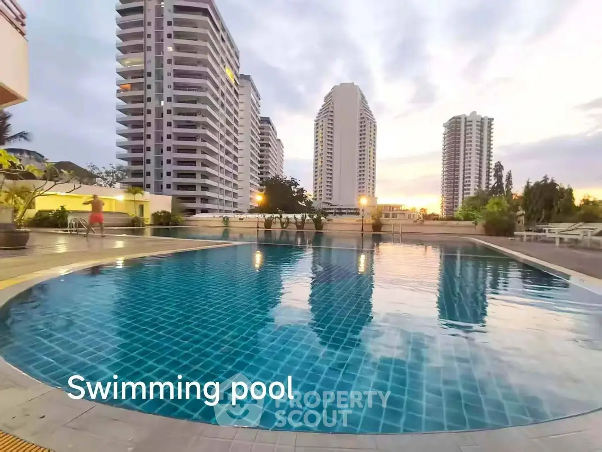 Luxurious swimming pool with stunning cityscape view at sunset, perfect for relaxation and leisure.