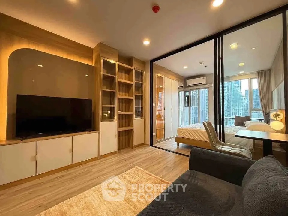 Modern living room with open layout and city view, featuring sleek furniture and large windows.